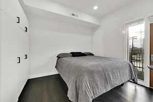 Bedroom featuring visible vents, dark wood-style flooring, baseboards, and access to outside