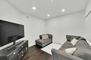 Living area with dark wood finished floors, recessed lighting, baseboards, and visible vents