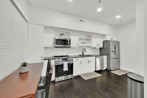 Kitchen featuring open shelves, a sink, backsplash, dark countertops, and appliances with stainless steel finishes