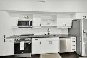 Kitchen featuring a sink, open shelves, visible vents, and stainless steel appliances