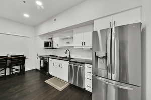 Kitchen featuring dark countertops, visible vents, decorative backsplash, stainless steel appliances, and a sink