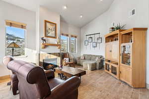 Living area featuring visible vents, plenty of natural light, a fireplace, and light wood-style flooring