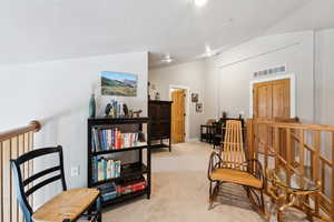 Living area featuring light carpet, an upstairs landing, visible vents, and lofted ceiling