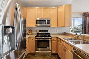 Kitchen featuring a sink, stainless steel appliances, light brown cabinets, and light countertops