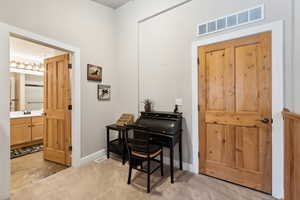 Entryway featuring visible vents, light carpet, and baseboards