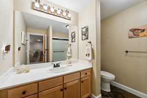 Full bath with baseboards, toilet, a shower with shower door, tile patterned floors, and vanity