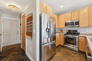 Kitchen with light brown cabinets, stone finish flooring, light countertops, recessed lighting, and appliances with stainless steel finishes