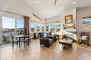 Living area with a wealth of natural light, a stone fireplace, and wood finished floors