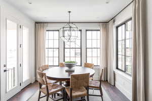 Dining area featuring dark wood finished floors, an inviting chandelier, plenty of natural light, and baseboards
