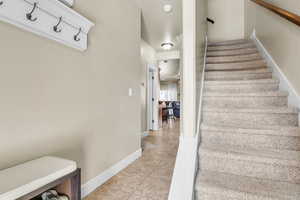 Staircase featuring tile patterned flooring, a ceiling fan, and baseboards
