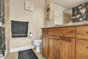 Bathroom with tile patterned floors, curtained shower, toilet, and baseboards