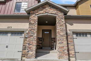 Doorway to property with board and batten siding, stone siding, and stucco siding