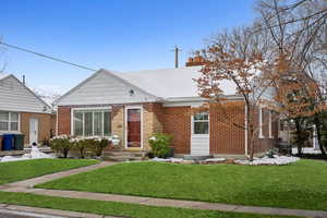 View of front facade featuring brick siding, a chimney, and a front yard