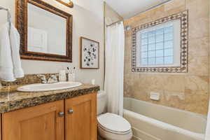 Full bath with vanity, shower / tub combo, and toilet