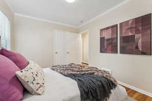 Bedroom featuring baseboards, wood finished floors, and crown molding