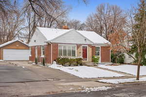 View of front of home with brick siding, a chimney, a garage, and an outdoor structure