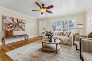 Living area featuring visible vents, ornamental molding, a ceiling fan, wood finished floors, and baseboards