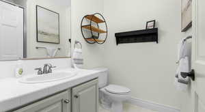 Bathroom featuring baseboards, toilet, and vanity