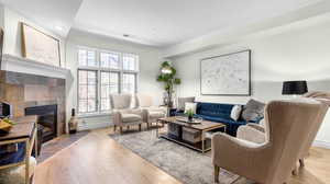 Living area featuring a tiled fireplace, visible vents, light wood-type flooring, and baseboards
