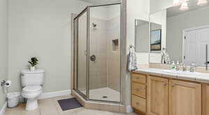 Bathroom featuring vanity, toilet, a shower stall, and tile patterned flooring