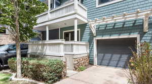 Property entrance with concrete driveway, a balcony, a garage, and covered porch