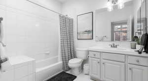 Full bath featuring tile patterned floors, toilet, vanity, and shower / tub combo