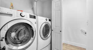 Laundry area featuring laundry area, light wood-style flooring, washer and dryer, and baseboards