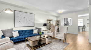 Living area featuring baseboards, wood-type flooring, and crown molding