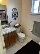 Half bath with tile patterned floors, toilet, and vanity