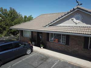 View of front of home with brick siding, uncovered parking, fence, and a tile roof