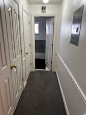 Hall featuring electric panel, baseboards, a textured ceiling, and dark carpet