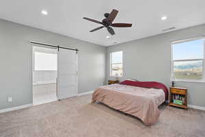 Bedroom with a barn door, recessed lighting, visible vents, baseboards, and carpet