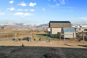 View of yard with an outbuilding, a rural view, fence, and a mountain view