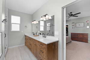 Bathroom with baseboards, double vanity, a sink, and a shower stall