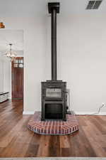 Room details featuring a wood stove, baseboards, visible vents, and wood finished floors