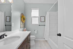 Full bath featuring toilet, shower / tub combo, baseboards, and vanity