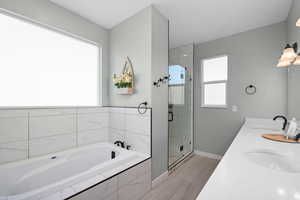 Full bathroom with a stall shower, a sink, baseboards, and a bath