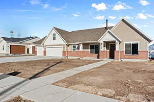 View of front of property with board and batten siding, concrete driveway, brick siding, and roof with shingles