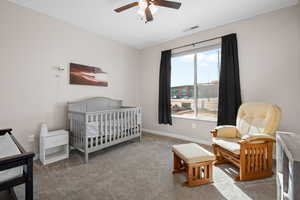 Bedroom featuring carpet, visible vents, ceiling fan, a nursery area, and baseboards