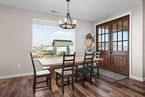 Dining space with french doors, a wealth of natural light, dark wood finished floors, and visible vents