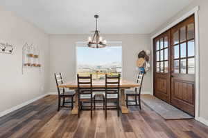 Dining area featuring baseboards, dark wood finished floors, and an inviting chandelier