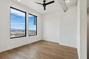 Spare room featuring visible vents, wood finished floors, baseboards, and ceiling fan