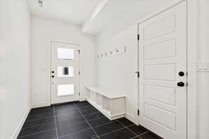 Mudroom with a wealth of natural light, visible vents, baseboards, and dark tile patterned flooring