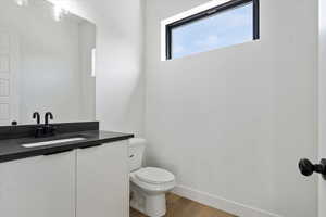 Bathroom with vanity, toilet, wood finished floors, and baseboards