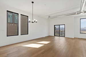 Unfurnished room with an inviting chandelier, baseboards, and wood finished floors