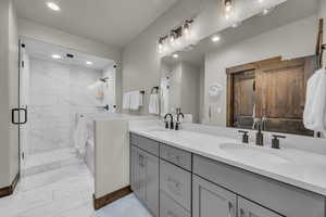 Bathroom with recessed lighting, marble finish floor, a shower stall, and a sink