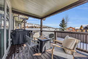 Snow covered deck featuring an outdoor fire pit, a mountain view, and a grill