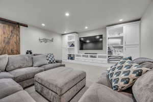 Living room featuring a barn door, recessed lighting, and carpet floors