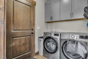 Laundry room featuring washer and dryer, cabinet space, and baseboards
