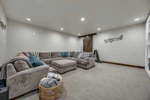 Living area with recessed lighting, a barn door, baseboards, and light colored carpet
